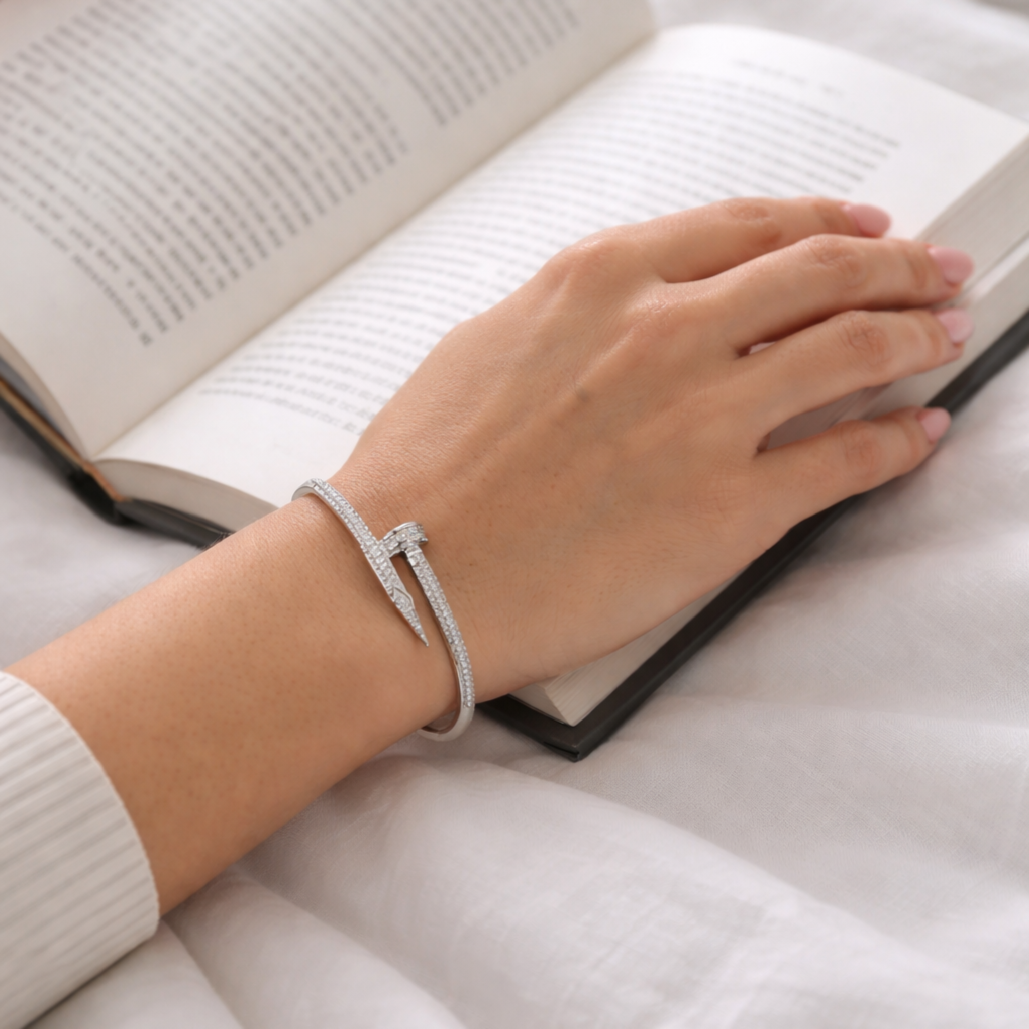 Person reading a book with a bracelet on a white surface